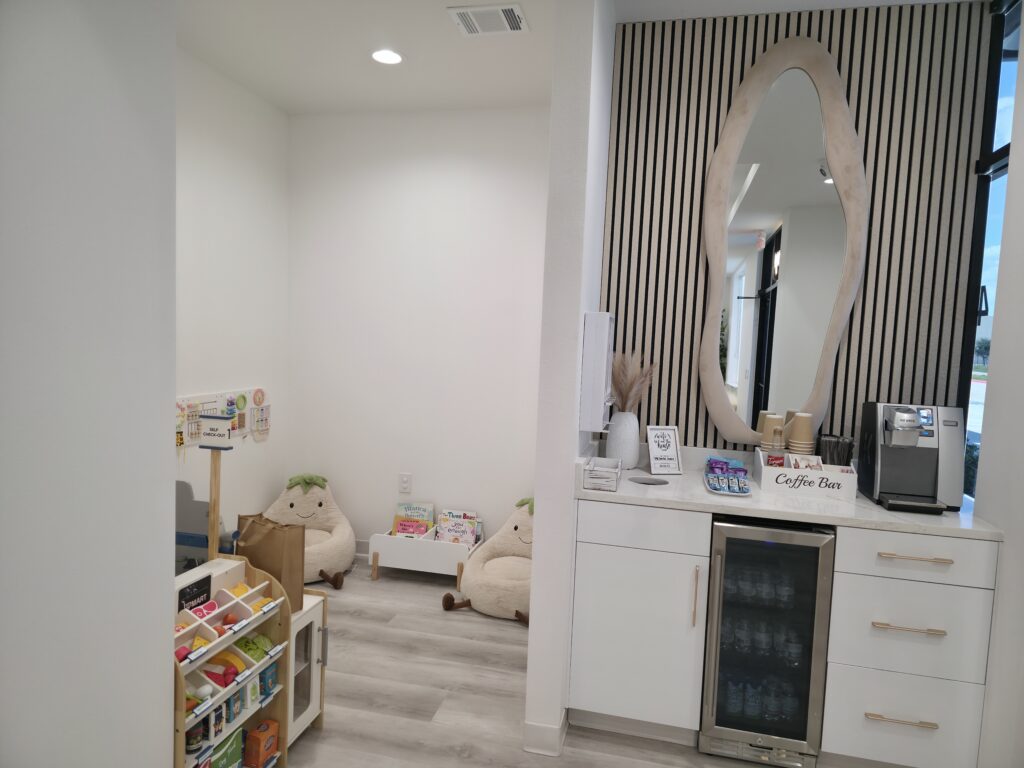 Calm waiting area with a cozy kids' reading corner and coffee bar at MK Dental Studio in Fulshear, TX