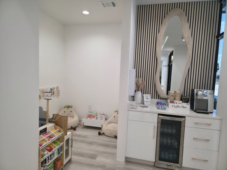 Calm waiting area with a cozy kids' reading corner and coffee bar at MK Dental Studio in Fulshear, TX